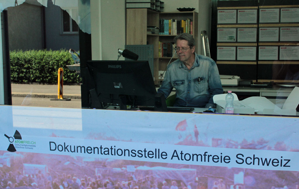 Blick durch das Schaufenster der Dokumentationsstelle Atomfrei Schweiz, Aernschd Born bei der Arbeit.