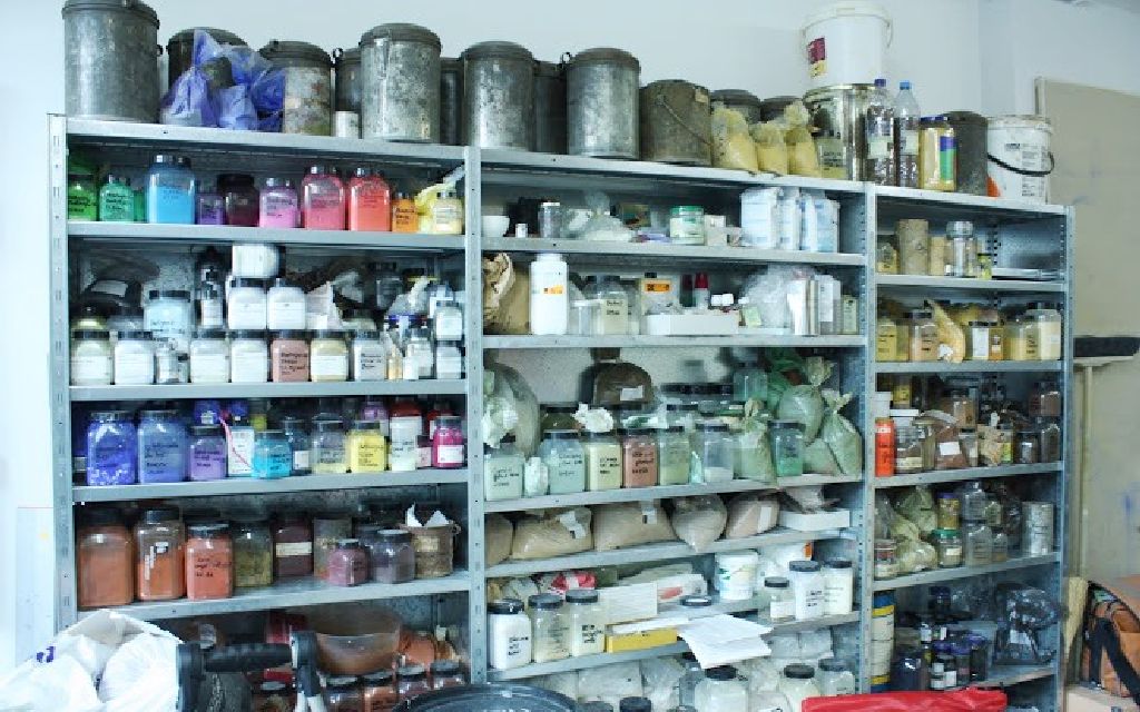 Regal voller Gläser mit farbiger Erde drin