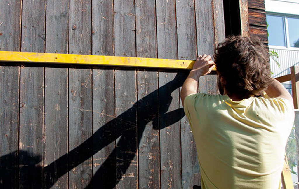 Ein Mann vermisst etwas an einer Holzwand.
