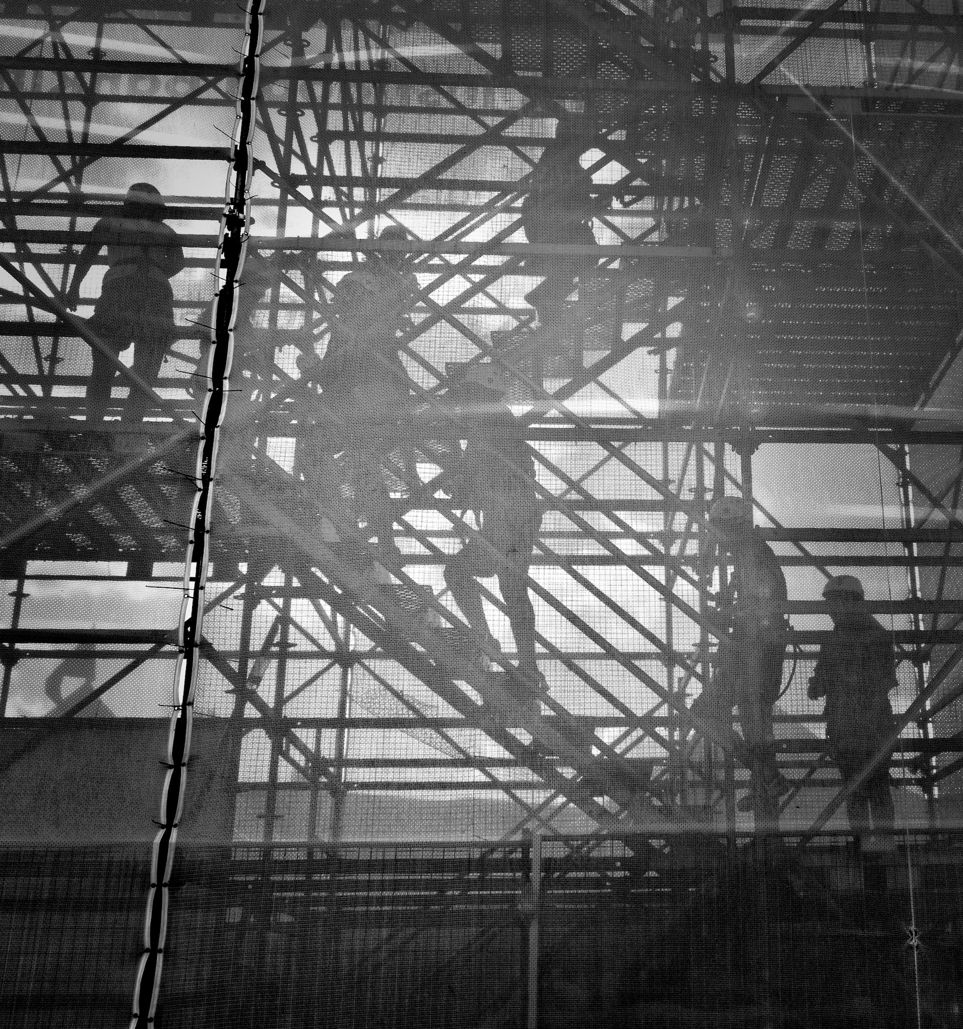 Die Schatten von Bauarbeitern auf einem Baugerüst an einer Betonwand.
