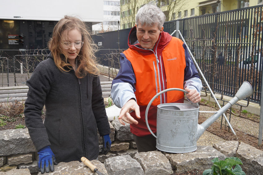 Zwei Personen mit Gieskanne