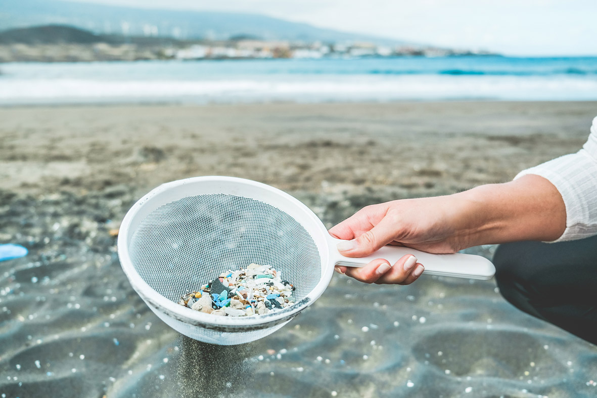 Frau filtert den Sand von Plastik