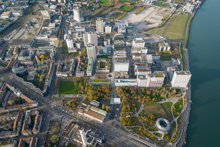 Heute stehen auf dem Novartis-Campus über 2000 Bäume und es wird grossen Wert auf nachhaltige Gebäudeentwicklung gelegt. So besteht die gesamte Tragkonstruktion des Pavillons (das runde Gebäude unten rechts) aus Holz; die Fassade ist mit etwa 10‘000 organischen Photovoltaik-Zellen sowie mit LEDs ausgestattet.