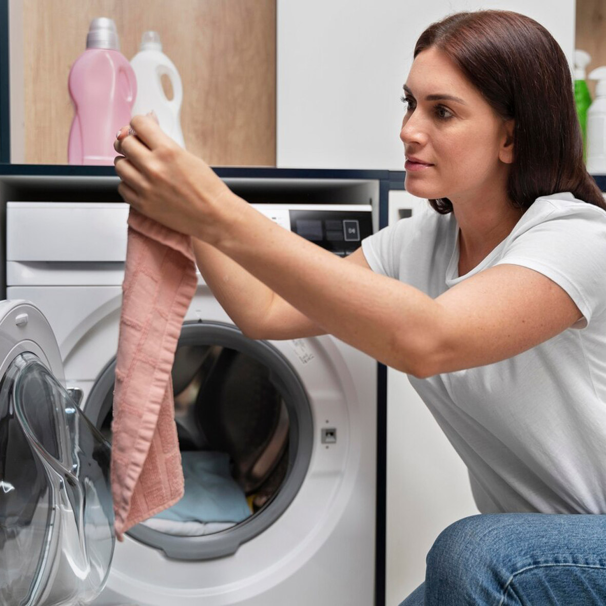 Frau entnimmt sauber Kleidung aus Waschmaschine