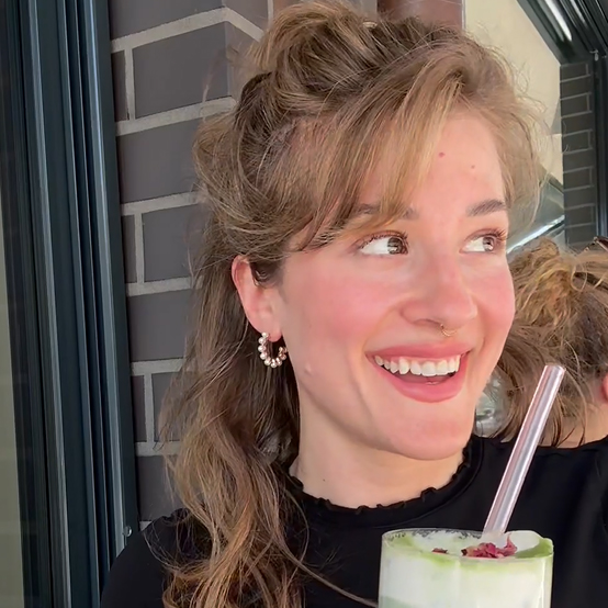 Sophie lächelt und hält ein Getränk in ihrer Hand.