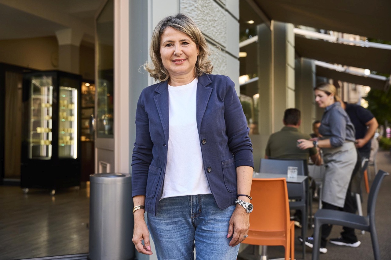 Carmela Petitjean-Guglielmino steht und lächelt ausserhalb ihres Cafés in die Kamera.