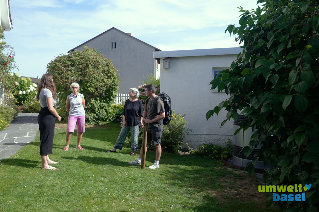 Das Bild zeigt einen Hintergarten, wo vier Personen in einem Kreis stehen.