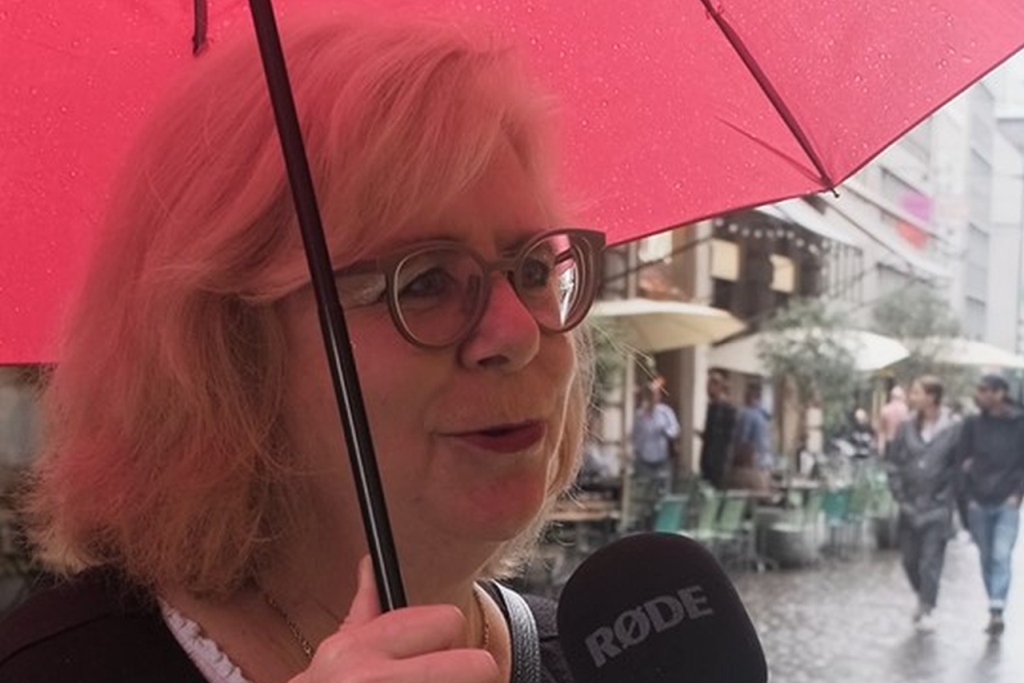 Eine Frau wird auf der Strasse im Regen befragt.