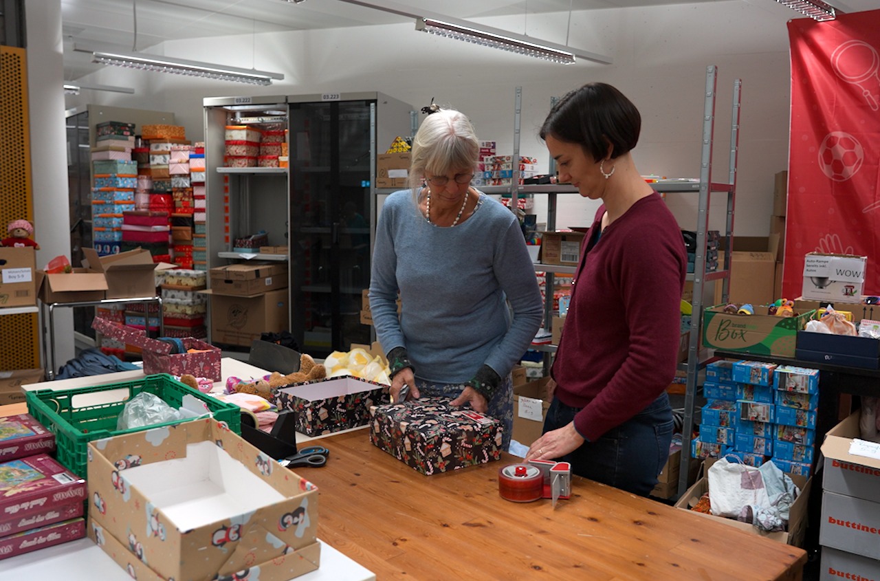 Zwei Personen verpacken einen Schuhkarton in der Werkstatt.