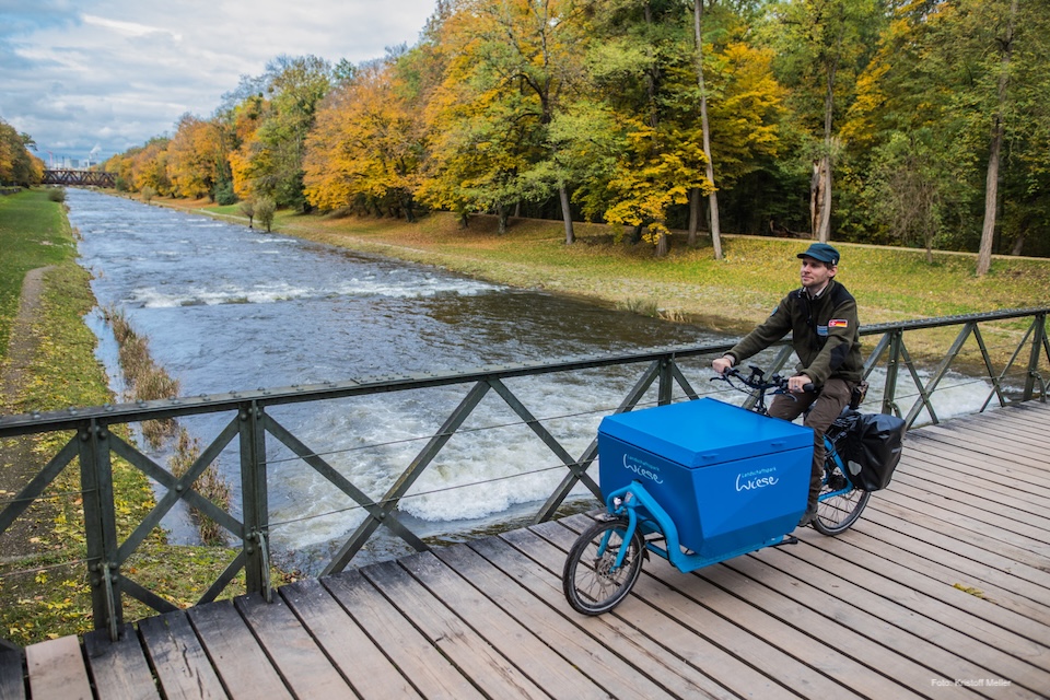 Ranger des Landschaftsparks Wiese mit Lastenvelo auf einer Brücke