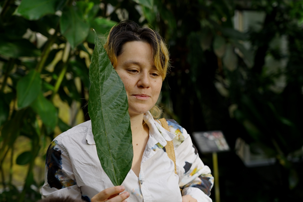 Ayaka Gütlin, die Koordinatorin der Grünen Schule, hält eine Kakaobohnenblatt in der Hand.