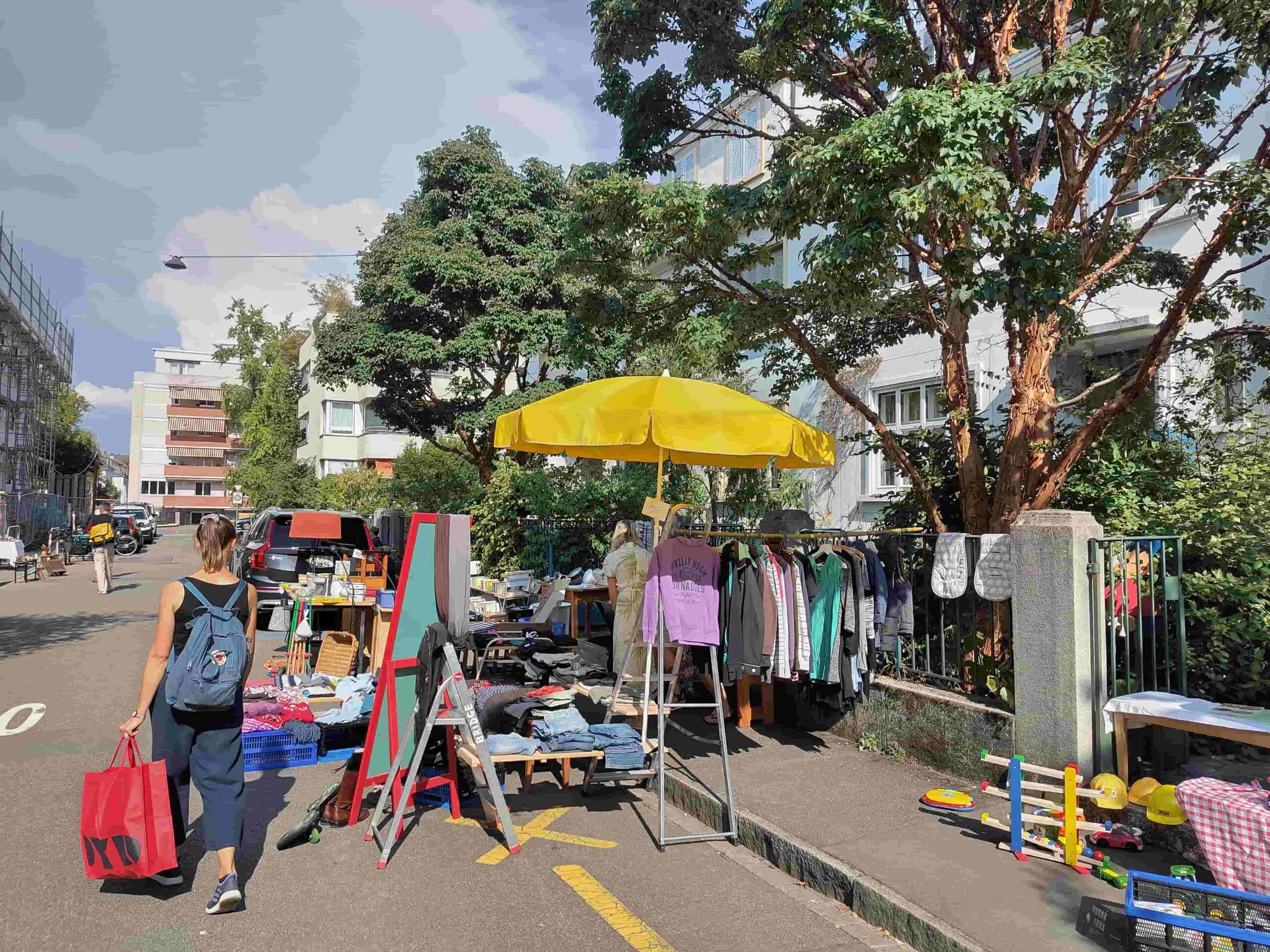 Flohmarktstand mit Sonnenschirm auf Trottoir und Strasse