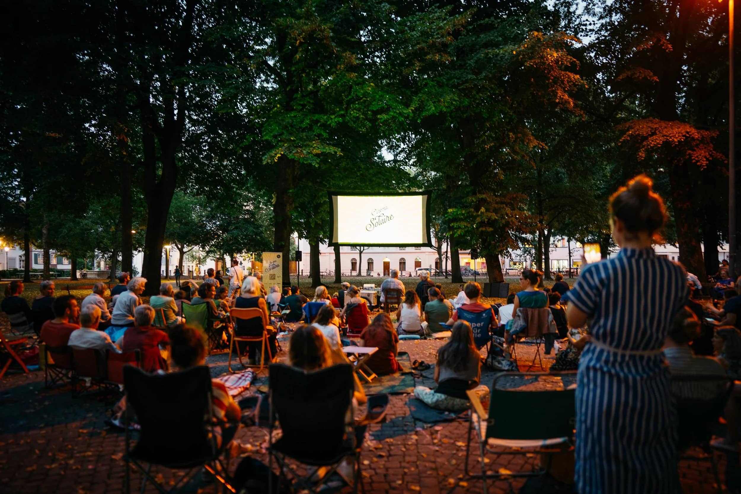 Publikum und Kinoleinwand auf dem abendlichen Petersplatz
